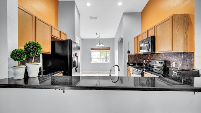 kitchen with sink, kitchen peninsula, dark stone counters, decorative backsplash, and black appliances