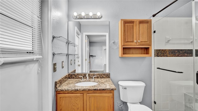 bathroom with vanity, a shower with shower door, and toilet