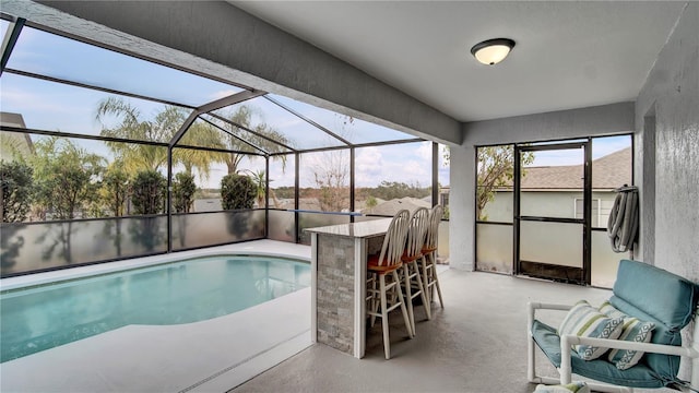 view of pool featuring glass enclosure, an outdoor bar, and a patio area