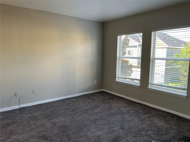 spare room with dark colored carpet