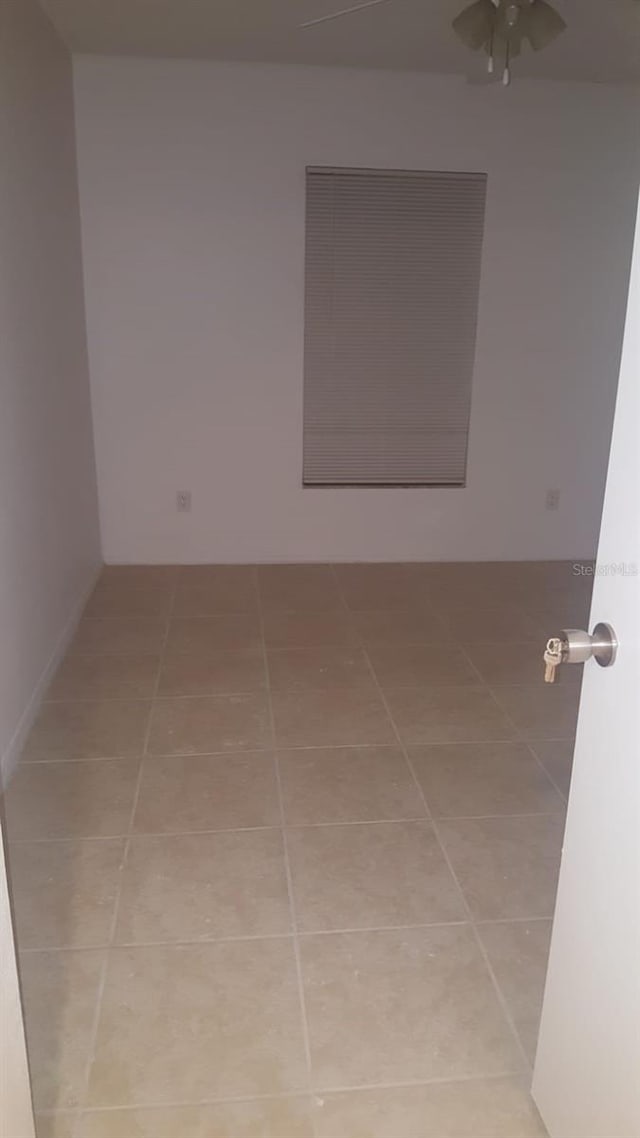 tiled spare room featuring ceiling fan