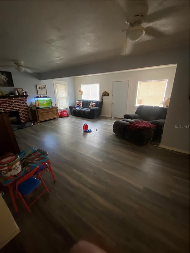 interior space featuring a fireplace, ceiling fan, and dark hardwood / wood-style flooring