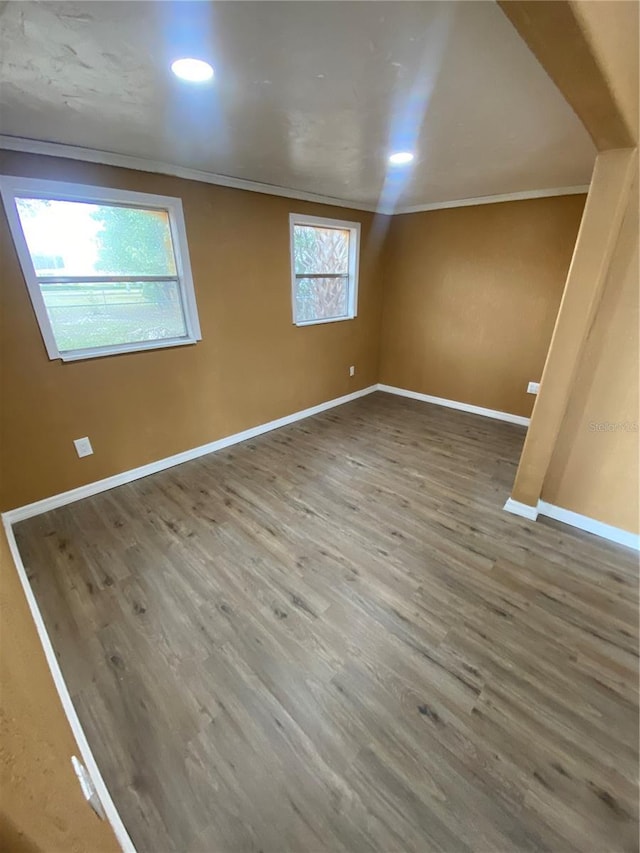 empty room with crown molding and wood-type flooring