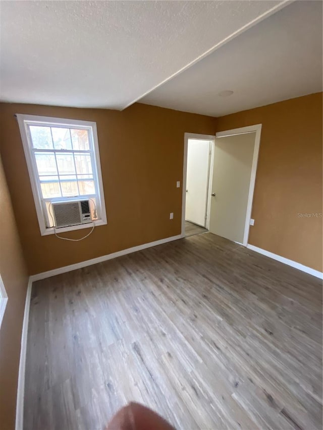 unfurnished room with cooling unit, a textured ceiling, and hardwood / wood-style floors