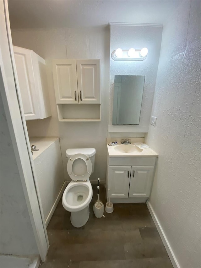 bathroom with toilet, wood-type flooring, and vanity