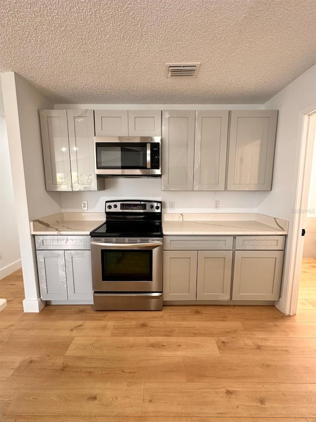 kitchen featuring gray cabinets, stainless steel appliances, and light hardwood / wood-style floors