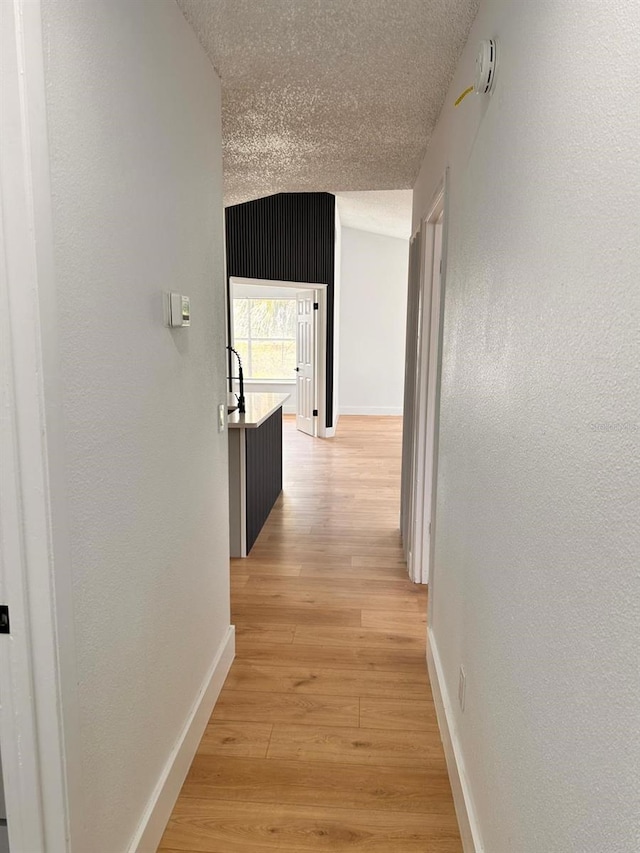 hallway with light hardwood / wood-style floors and a textured ceiling