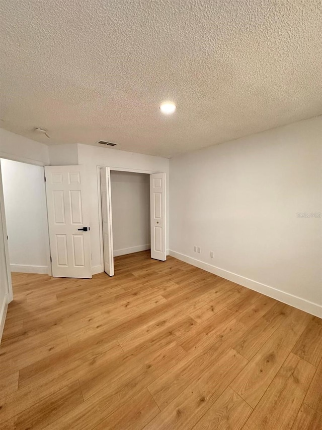 unfurnished bedroom with light hardwood / wood-style floors, a closet, and a textured ceiling