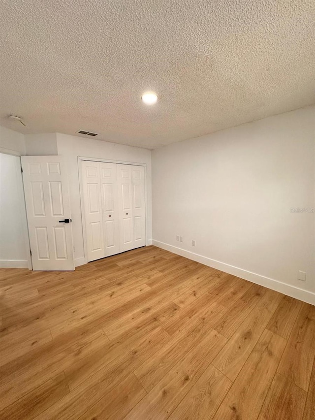 unfurnished bedroom with a closet, a textured ceiling, and light hardwood / wood-style flooring