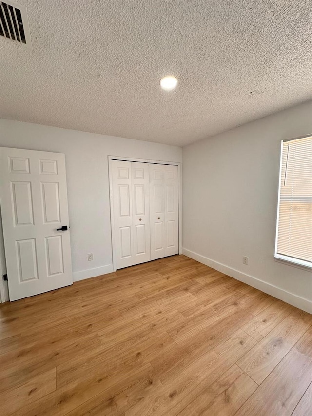 unfurnished bedroom with a closet, a textured ceiling, and light wood-type flooring