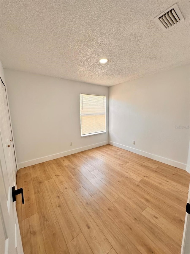 unfurnished room with light hardwood / wood-style floors and a textured ceiling