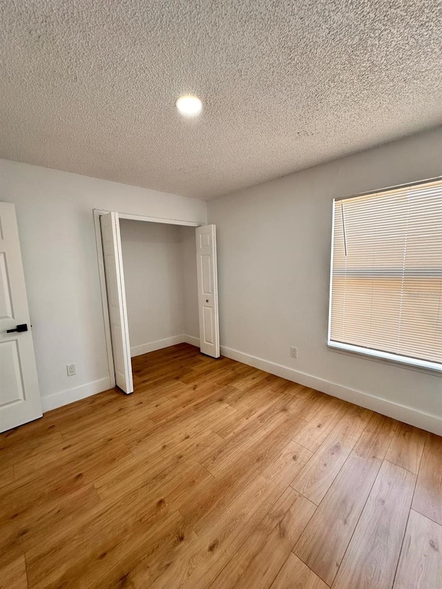 unfurnished bedroom featuring light hardwood / wood-style flooring, a closet, and a textured ceiling