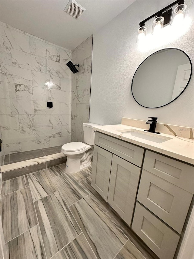 bathroom featuring vanity, toilet, and tiled shower