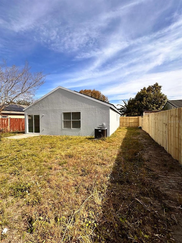 rear view of house featuring central AC and a lawn