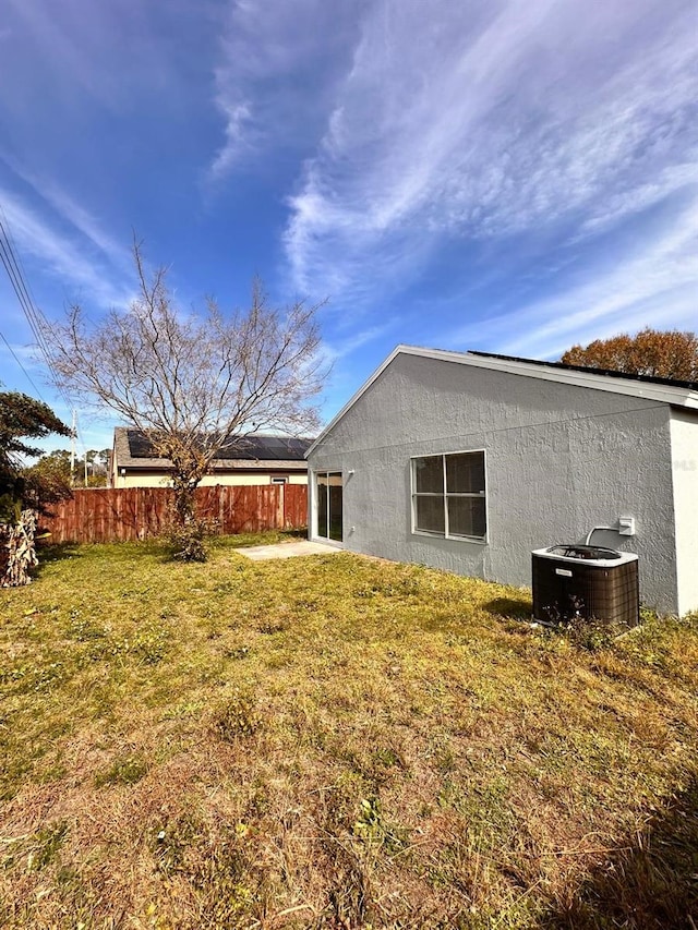 exterior space with central AC unit and a lawn