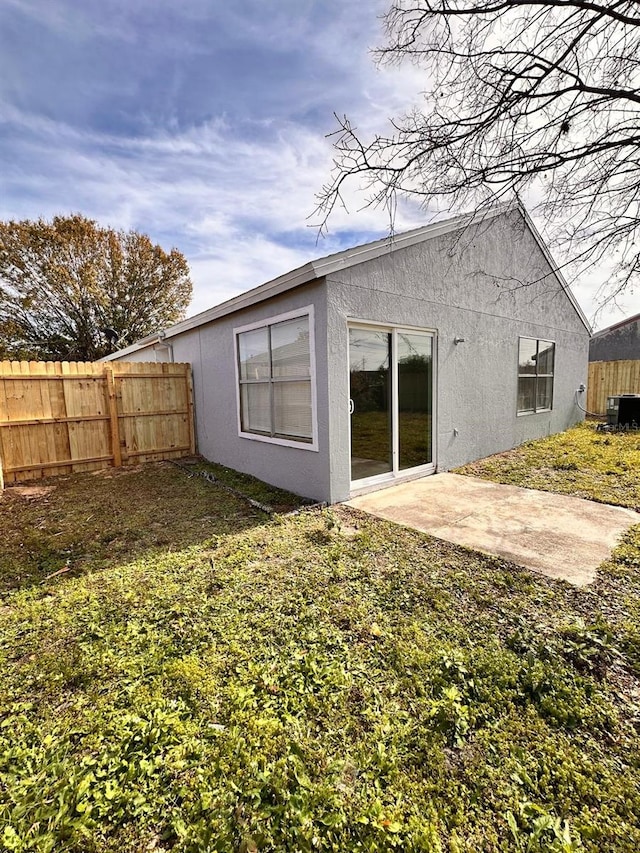 back of house with cooling unit, a yard, and a patio area