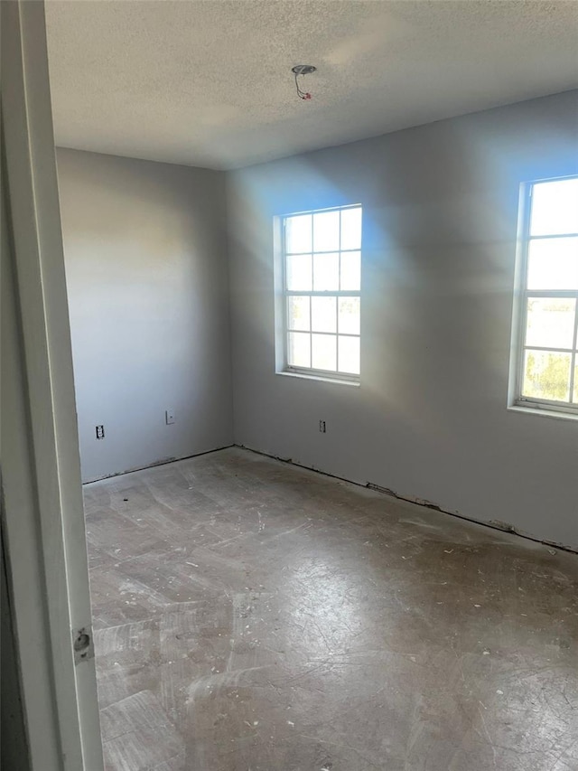 unfurnished room with a wealth of natural light and a textured ceiling