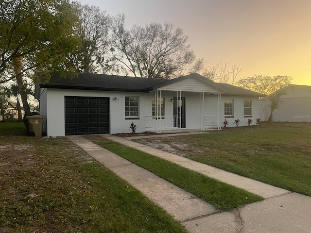 single story home with an attached garage, covered porch, and a front lawn