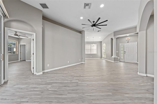 unfurnished living room with ceiling fan with notable chandelier, light hardwood / wood-style floors, and decorative columns