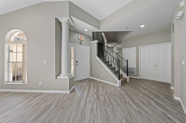 entryway with decorative columns, lofted ceiling, and light hardwood / wood-style flooring