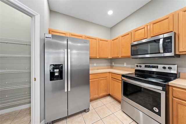 kitchen featuring appliances with stainless steel finishes, light tile patterned floors, and light brown cabinets