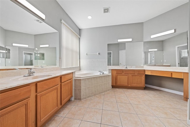 bathroom featuring a relaxing tiled tub, vanity, and tile patterned flooring