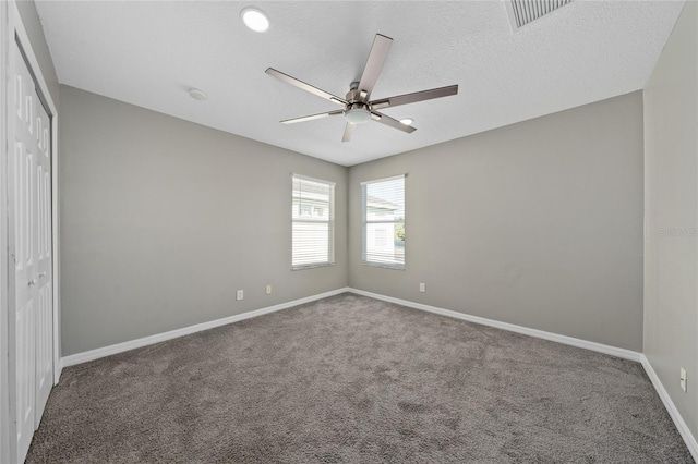 carpeted empty room featuring ceiling fan and a textured ceiling