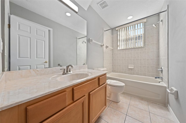 full bathroom with tiled shower / bath, tile patterned flooring, vanity, toilet, and a textured ceiling