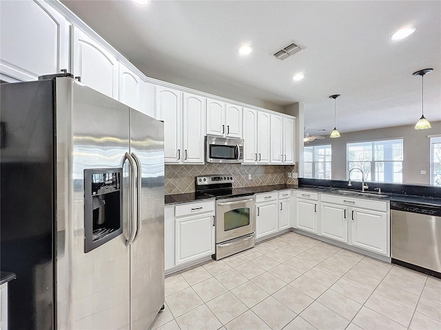 kitchen featuring decorative light fixtures, white cabinetry, sink, backsplash, and stainless steel appliances