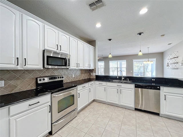 kitchen with sink, pendant lighting, stainless steel appliances, decorative backsplash, and white cabinets