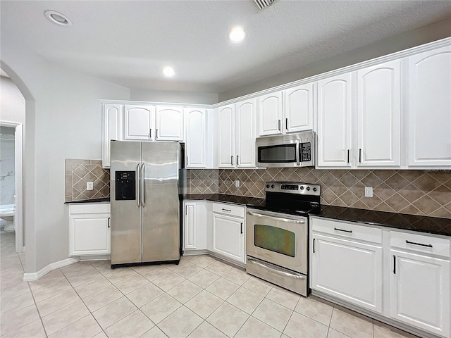 kitchen featuring light tile patterned flooring, appliances with stainless steel finishes, backsplash, and white cabinets