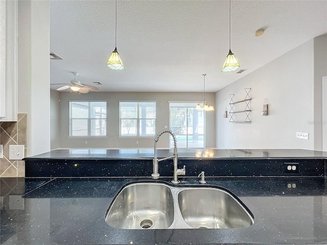 kitchen featuring hanging light fixtures, sink, and a textured ceiling