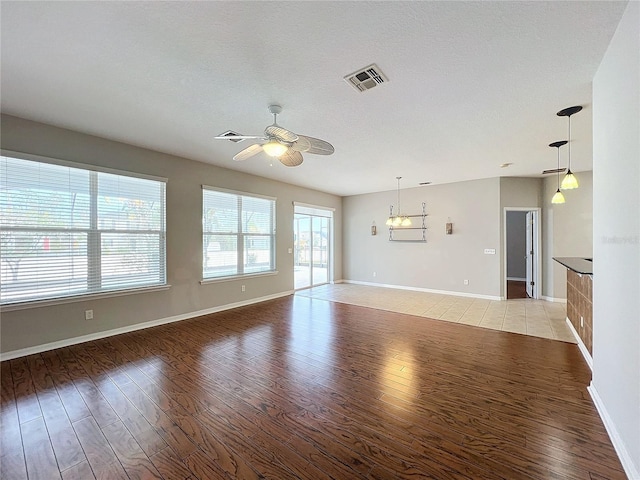 unfurnished living room with a healthy amount of sunlight, a textured ceiling, ceiling fan, and light hardwood / wood-style flooring