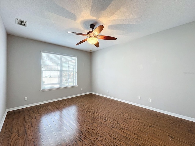 empty room with ceiling fan, dark hardwood / wood-style floors, and a textured ceiling