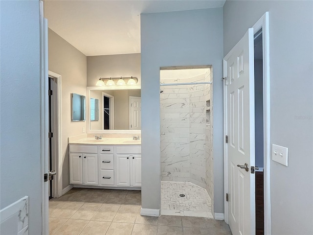 bathroom featuring tile patterned flooring, vanity, and a tile shower