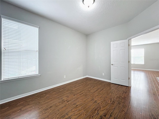 empty room with dark hardwood / wood-style flooring and a textured ceiling