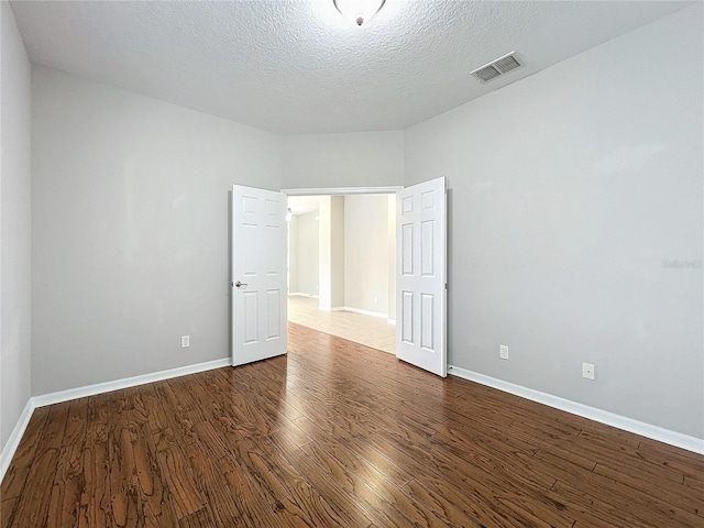 unfurnished room featuring dark wood-type flooring and a textured ceiling