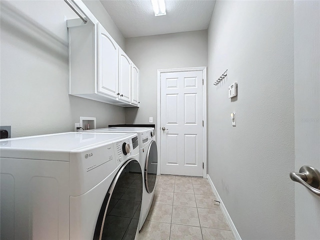 laundry room featuring cabinets, separate washer and dryer, a textured ceiling, and light tile patterned floors