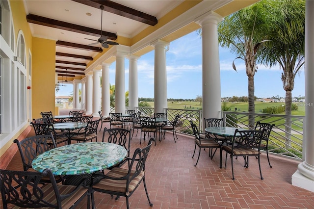 exterior space featuring beamed ceiling, ceiling fan, and ornate columns