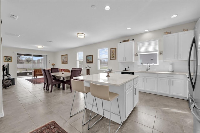 kitchen with white cabinetry, a center island, stainless steel refrigerator, and a healthy amount of sunlight