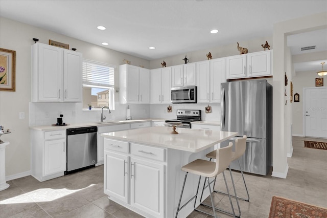 kitchen with tasteful backsplash, appliances with stainless steel finishes, a center island, and white cabinets