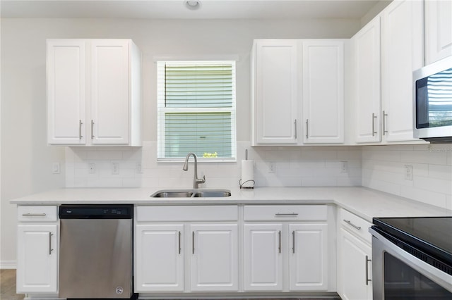 kitchen with white cabinetry, tasteful backsplash, a sink, and stainless steel appliances