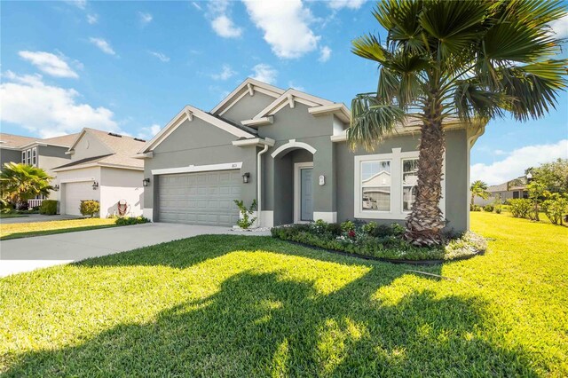 view of front of property featuring stucco siding, an attached garage, a front yard, and driveway