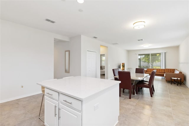 kitchen featuring open floor plan, light countertops, a center island, visible vents, and white cabinets