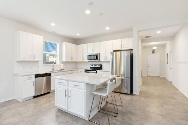 kitchen featuring a sink, stainless steel appliances, backsplash, and a kitchen island