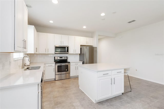 kitchen with a sink, backsplash, a kitchen island, appliances with stainless steel finishes, and visible vents