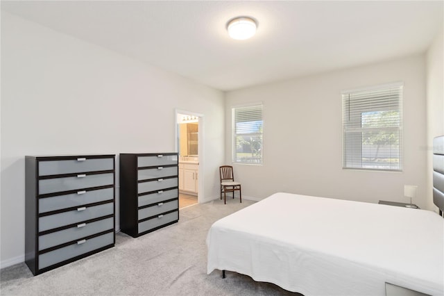 bedroom with connected bathroom, baseboards, and light colored carpet