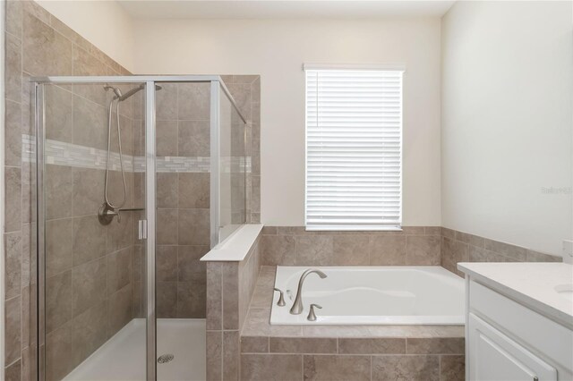 bathroom featuring a stall shower, vanity, and a garden tub