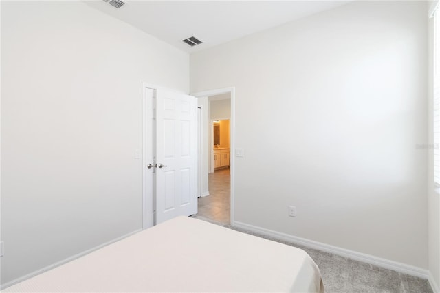 bedroom featuring baseboards, visible vents, and light carpet
