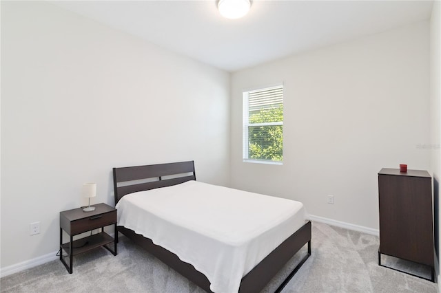 bedroom featuring light carpet and baseboards